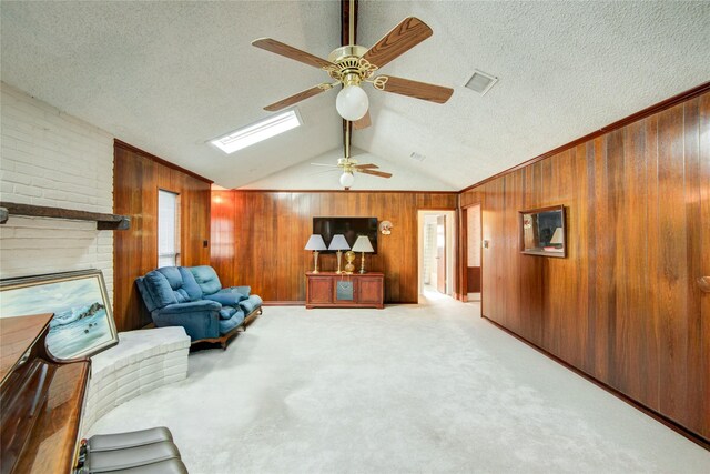 sitting room featuring carpet floors, wood walls, visible vents, and lofted ceiling with skylight