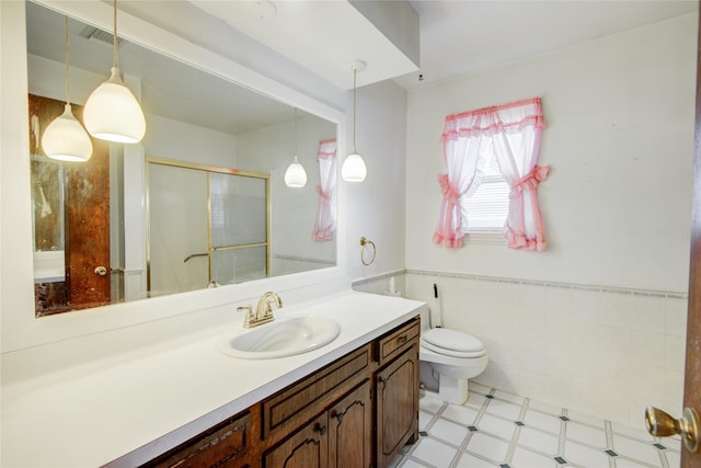 full bathroom with tile walls, toilet, a stall shower, wainscoting, and vanity