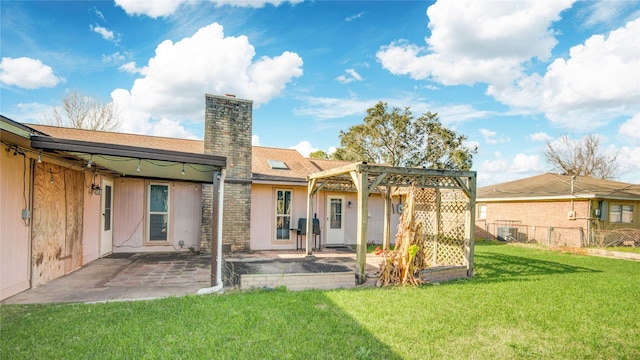 back of house featuring a shingled roof, a lawn, a patio, a chimney, and fence