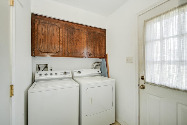 washroom with a wealth of natural light, cabinet space, and washer and clothes dryer