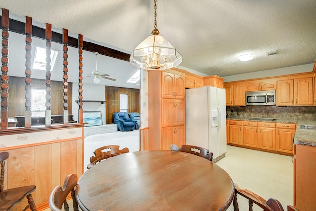 dining area with ceiling fan, a textured ceiling, vaulted ceiling with beams, wood walls, and visible vents