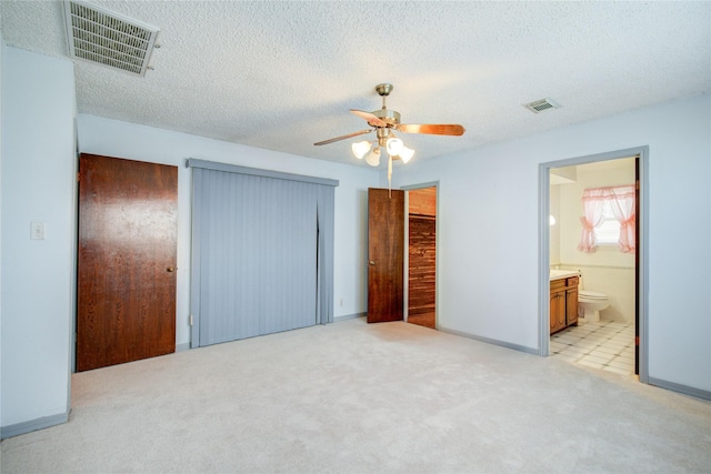 unfurnished bedroom featuring a textured ceiling, ceiling fan, visible vents, and light colored carpet