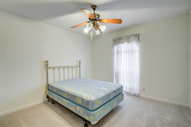 bedroom with light carpet, ceiling fan, and baseboards