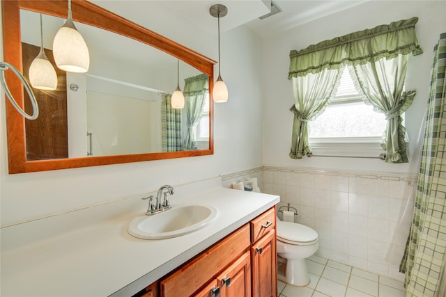 full bath featuring toilet, a wainscoted wall, tile walls, vanity, and tile patterned floors