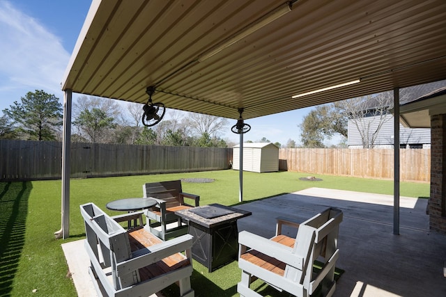 view of patio featuring a storage shed, a fire pit, a fenced backyard, and an outdoor structure