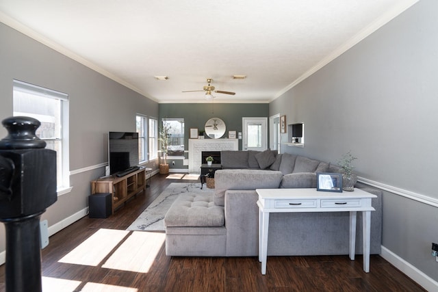 living area featuring crown molding, a brick fireplace, wood finished floors, and baseboards