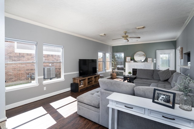 living area featuring plenty of natural light, a fireplace, dark wood finished floors, and visible vents