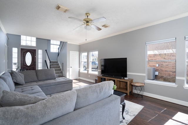 living area featuring wood finished floors, visible vents, baseboards, and stairs