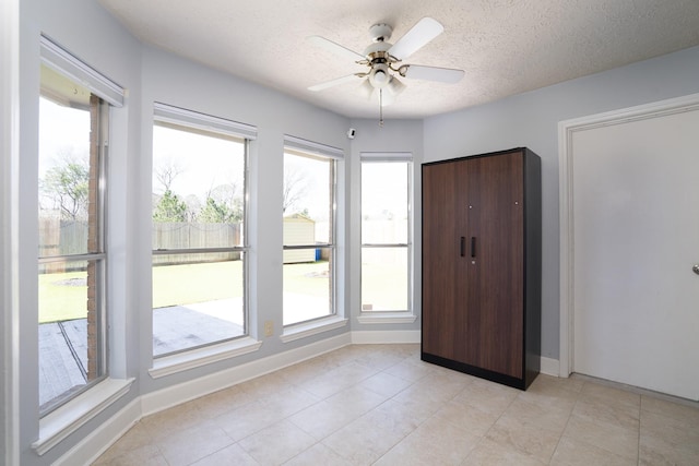 unfurnished bedroom featuring a textured ceiling, ceiling fan, light tile patterned floors, and baseboards