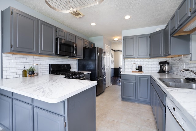 kitchen with a peninsula, light countertops, black appliances, a sink, and light tile patterned flooring