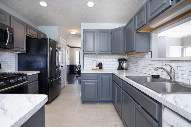 kitchen with light countertops, range with gas cooktop, stainless steel microwave, and a sink