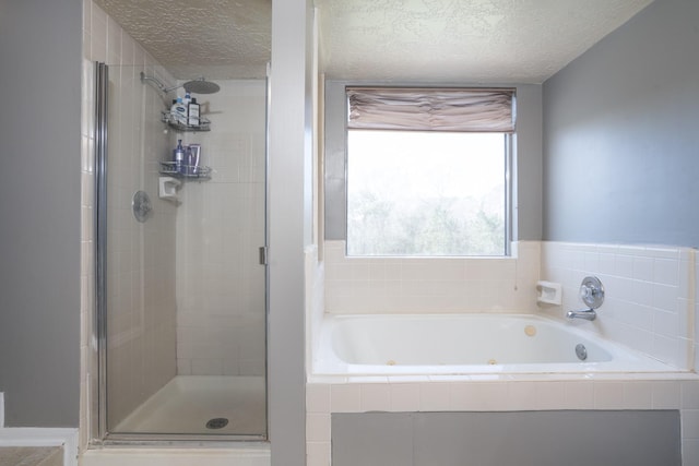 bathroom with a textured ceiling, a jetted tub, and a shower stall