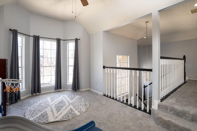 foyer featuring baseboards, ceiling fan, vaulted ceiling, a textured ceiling, and carpet flooring