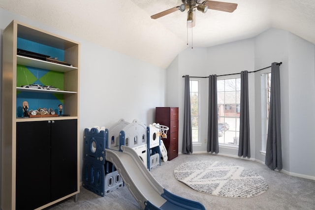 interior space featuring carpet floors, vaulted ceiling, baseboards, and ceiling fan