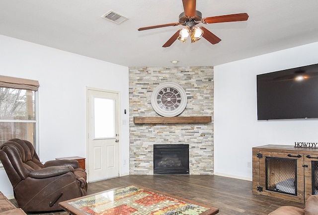 living area featuring a large fireplace, plenty of natural light, wood finished floors, and visible vents