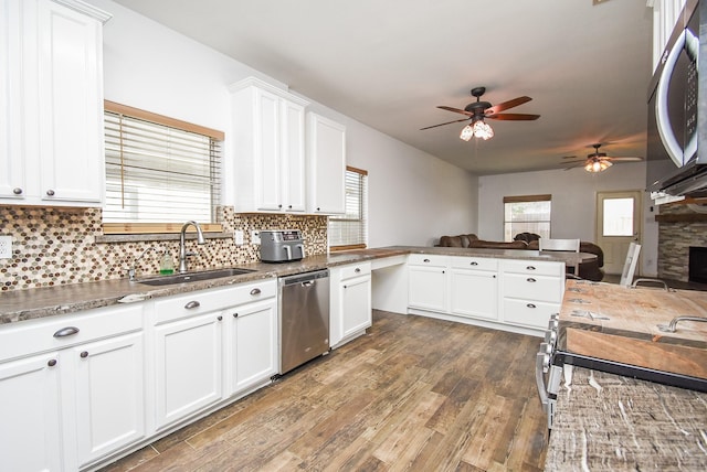 kitchen with plenty of natural light, appliances with stainless steel finishes, open floor plan, wood finished floors, and a sink