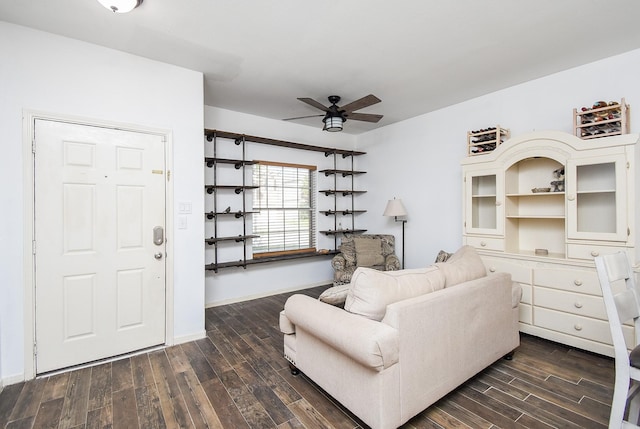 living room with baseboards, dark wood-type flooring, and a ceiling fan