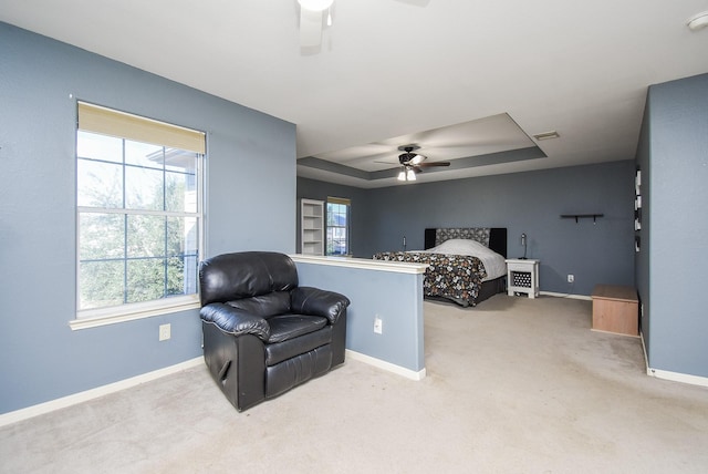 bedroom with carpet floors, a ceiling fan, visible vents, baseboards, and a tray ceiling