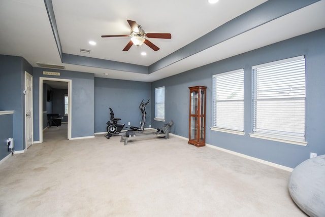 exercise room with carpet floors, a raised ceiling, and baseboards