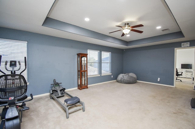 exercise room with a tray ceiling, visible vents, and carpet flooring