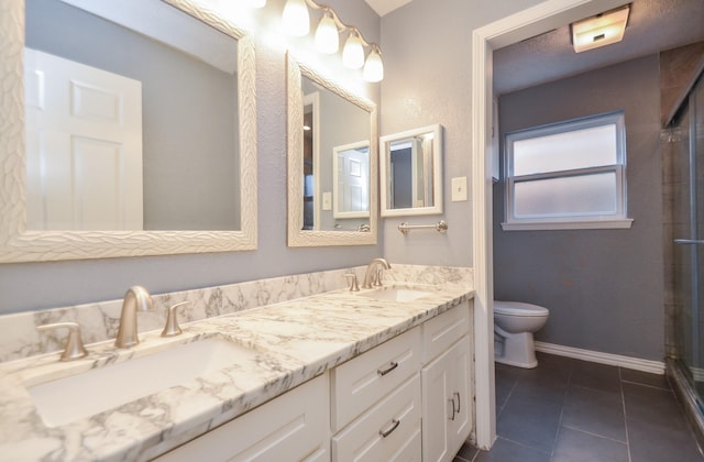 bathroom featuring tile patterned floors, toilet, baseboards, and a sink