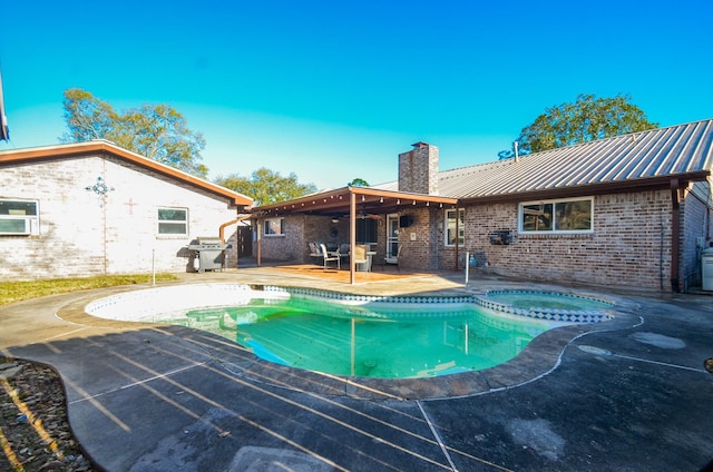 view of swimming pool featuring grilling area, a patio, and a pool with connected hot tub