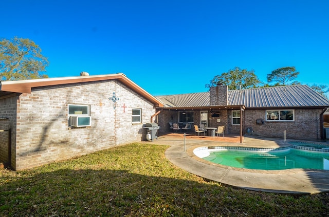 back of property featuring a yard, a chimney, a patio area, brick siding, and metal roof