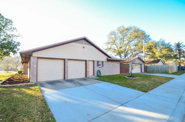 view of front of home with a front lawn, concrete driveway, fence, and brick siding