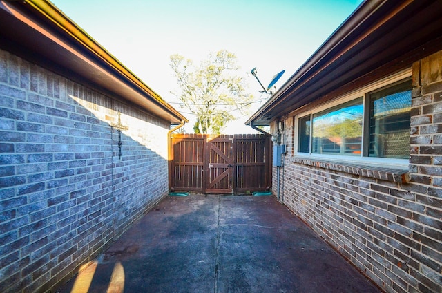 exterior space with a patio area, fence, brick siding, and a gate