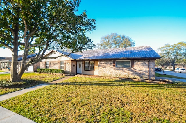 ranch-style home featuring brick siding, metal roof, and a front lawn