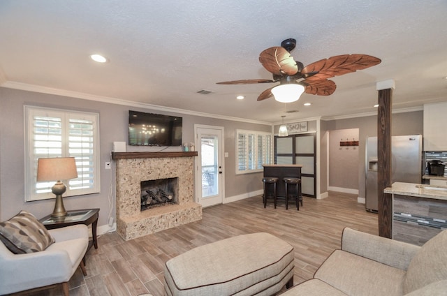 living area with light wood finished floors, visible vents, plenty of natural light, and ornamental molding