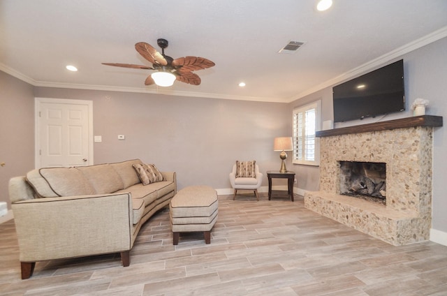 living area with a ceiling fan, baseboards, wood tiled floor, a fireplace with raised hearth, and crown molding