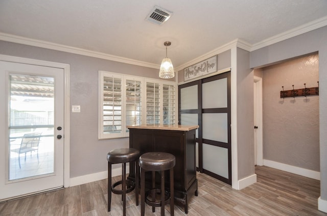 dining area with baseboards, wood finished floors, visible vents, and ornamental molding