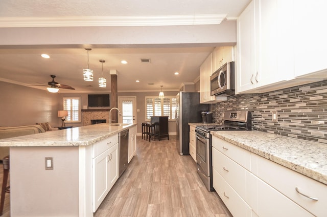 kitchen with a fireplace, ornamental molding, a sink, appliances with stainless steel finishes, and open floor plan