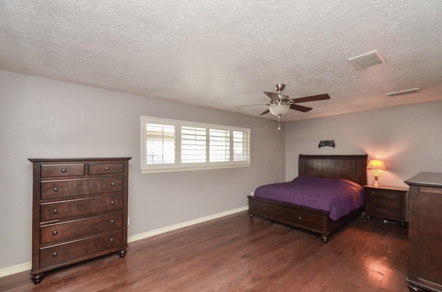 bedroom featuring dark wood finished floors, visible vents, a textured ceiling, and baseboards