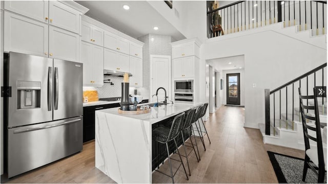 409 Silver Moon Way, Katy, TX 77493 - kitchen featuring appliances with stainless steel finishes, light countertops, light wood-style flooring, backsplash, and recessed lighting