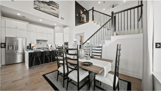 409 Silver Moon Way, Katy, TX 77493 - dining area featuring light wood finished floors, a high ceiling, stairs, and recessed lighting