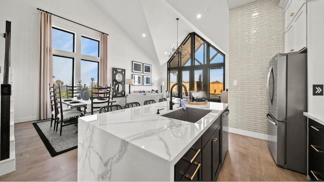409 Silver Moon Way, Katy, TX 77493 - kitchen featuring stainless steel appliances, a sink, high vaulted ceiling, light wood-style flooring, and baseboards