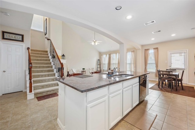 kitchen with dishwashing machine, dark stone countertops, visible vents, and a sink