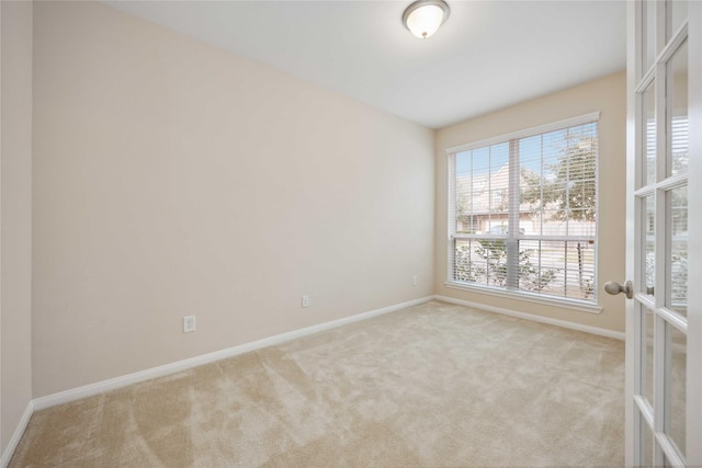 spare room featuring french doors, carpet flooring, and baseboards