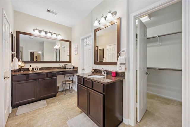 bathroom with tile patterned flooring, visible vents, vanity, and a spacious closet