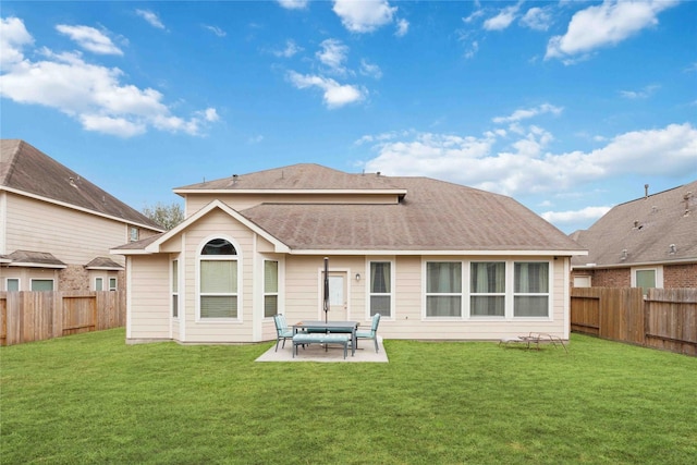 back of property with a fenced backyard, a shingled roof, a lawn, and a patio