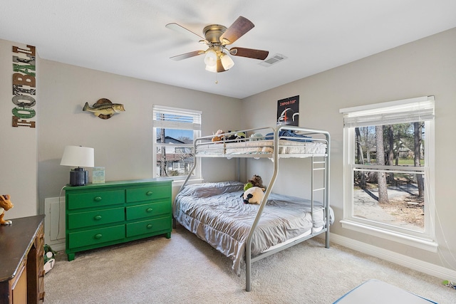 bedroom featuring visible vents, baseboards, light colored carpet, and a ceiling fan