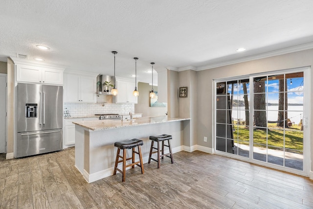 kitchen featuring tasteful backsplash, light stone countertops, wood finished floors, high end fridge, and white cabinetry