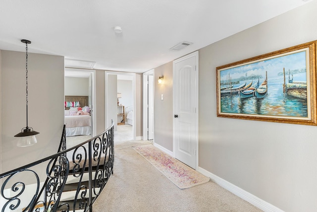 corridor with visible vents, light carpet, and baseboards