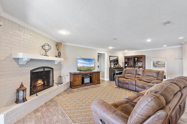 living room with visible vents, a textured ceiling, recessed lighting, crown molding, and a brick fireplace