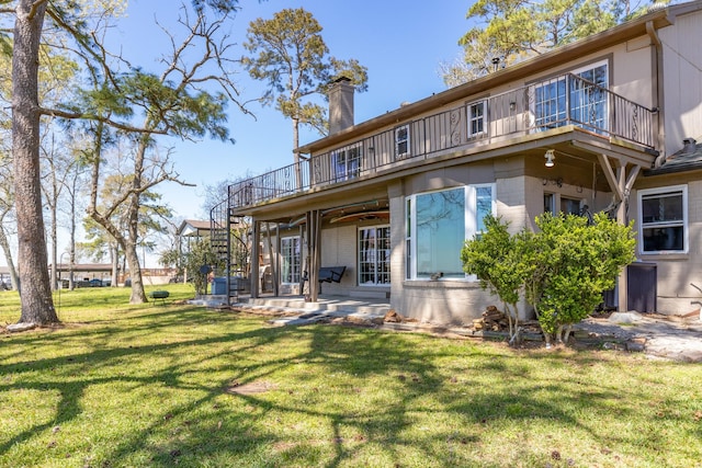 rear view of house featuring stairway, a chimney, a balcony, a yard, and a patio area