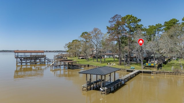 dock area with boat lift, a lawn, and a water view