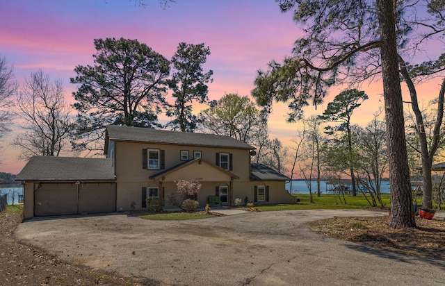 view of front of property with an attached garage, a water view, and dirt driveway