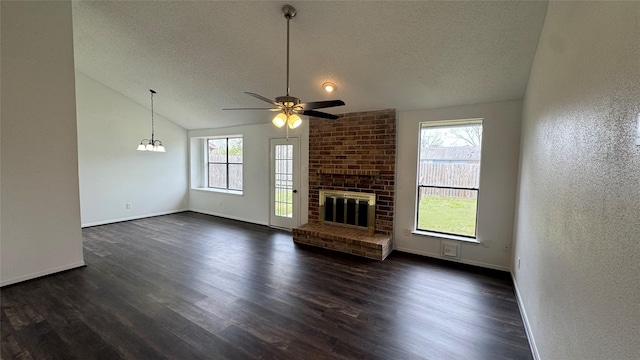 unfurnished living room featuring a ceiling fan, dark wood-style floors, vaulted ceiling, a textured ceiling, and a brick fireplace